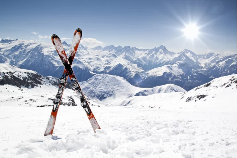 Skis plantés dans la neige aux Karellis avec vue sur les montagnes pour apprendre à skier en Savoie