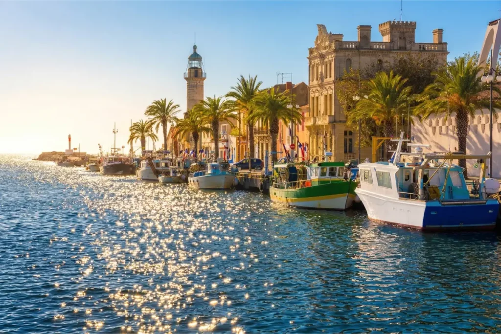 Port du Grau-du-Roi avec bateaux de pêche colorés, phare et quais bordés de palmiers en Camargue