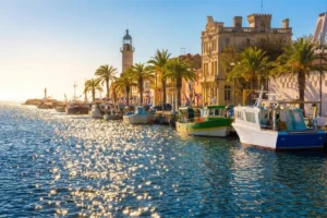Port du Grau-du-Roi avec bateaux de pêche colorés, phare et quais bordés de palmiers en Camargue