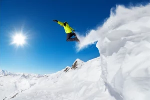 Snowboardeur en saut dans la poudreuse à La Clusaz dans les Alpes pour un séjour ski freestyle