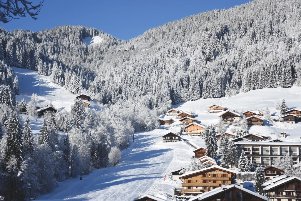 Village de montagne de La Clusaz sous la neige avec chalets traditionnels savoyards et pistes de ski en Haute-Savoie