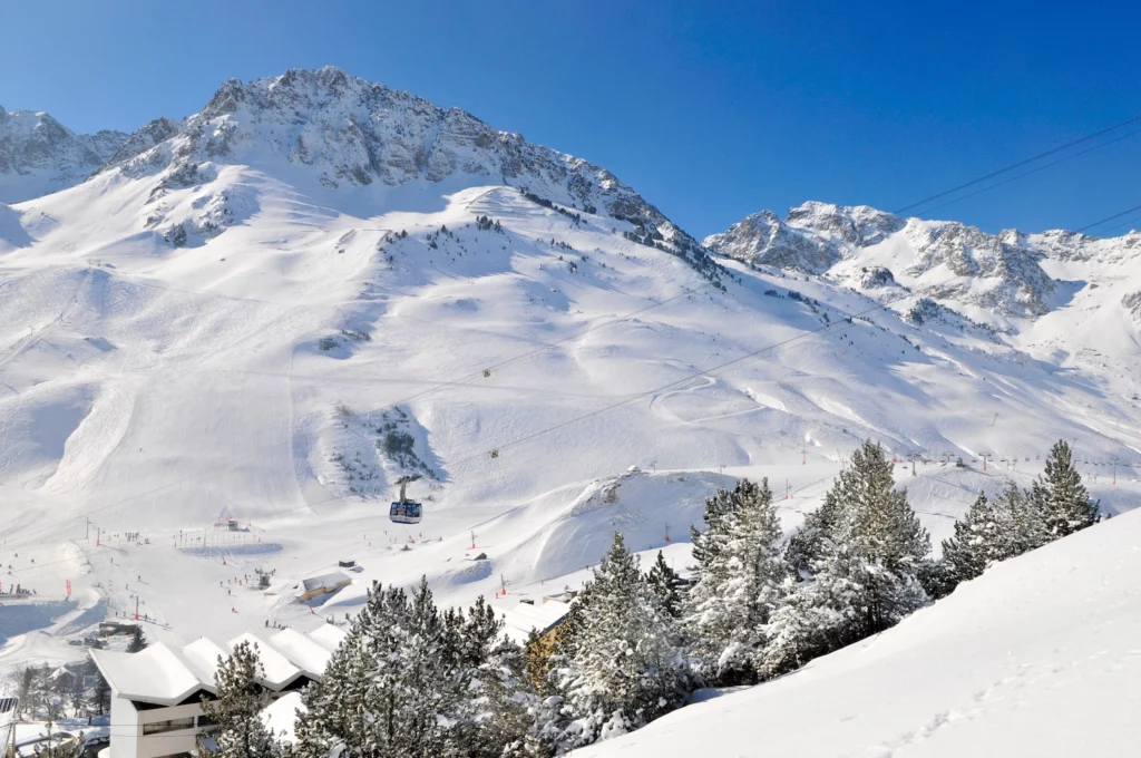 Domaine skiable de La Mongie avec téléphérique et pistes enneigées sous un ciel bleu dans les Hautes-Pyrénées