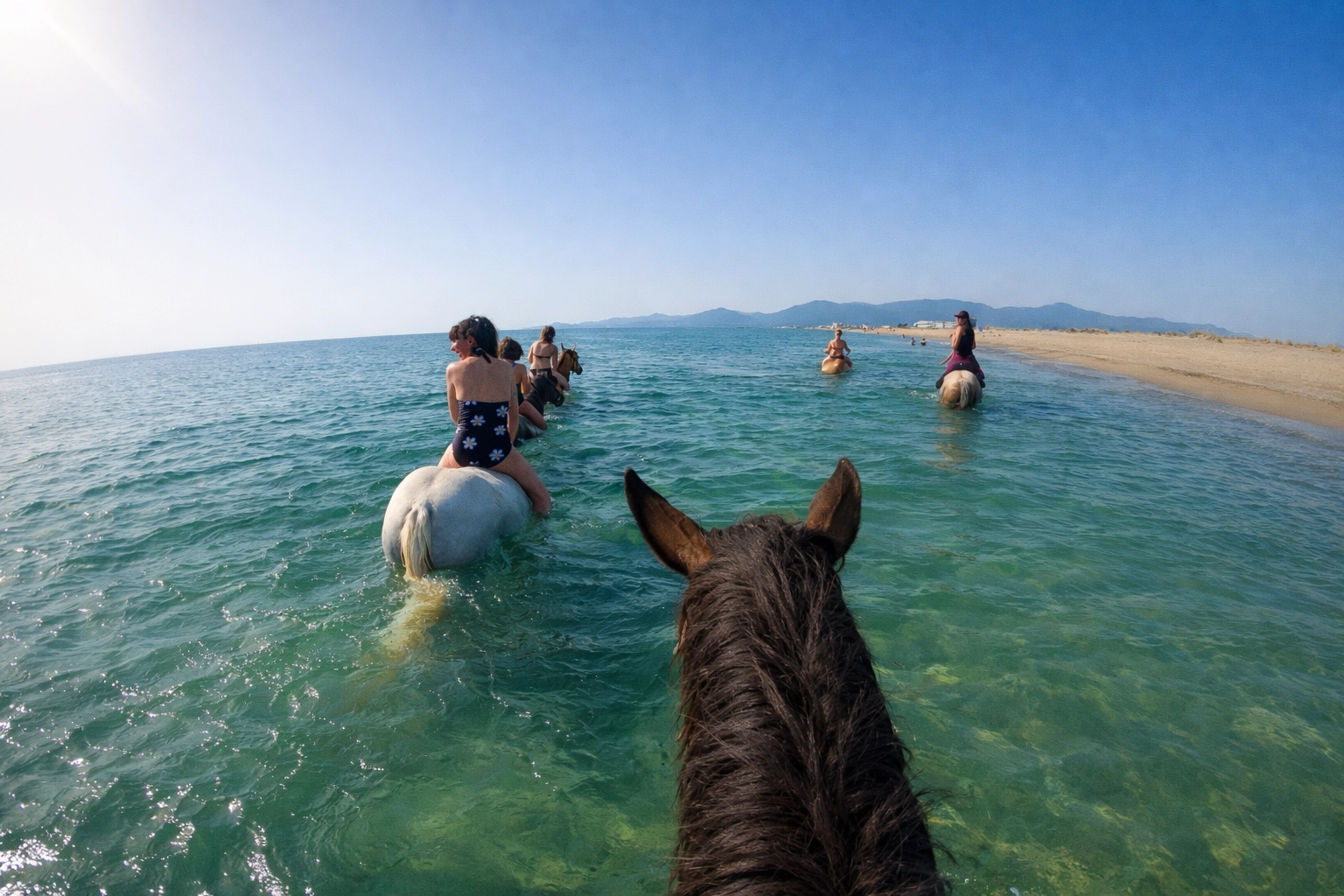Balade à cheval dans l'eau turquoise de la plage de Saint-Cyprien avec vue sur les montagnes
